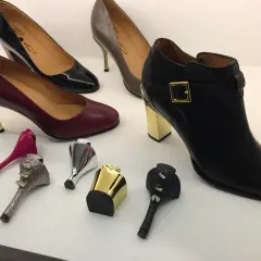 Buty z wymiennymi obcasami: czarne botki, bordowe i czarne szpilki, szare czółenka oraz ozdobne obcasy.