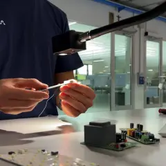 Técnico ensambla componentes electrónicos bajo una luz focalizada, asegurando cada lumen unidad.