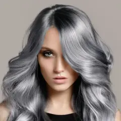 Frau mit voluminösem, welligem Haar in einem modernen balayage grau Farbton.