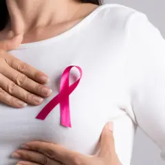Kobieta z różową wstążką na piersi, symbolem walki z rakiem. W tle subtelne nawiązanie do leczenia, np. tamoxifen.