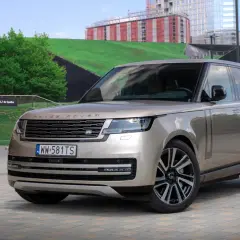 Elegancki Range Rover 2025 w kolorze piaskowym prezentuje się na tle nowoczesnej architektury.