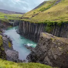 Un río turquesa serpentea entre cañones de basalto en Islandia, evocando la majestuosidad de los fiordos islandeses.