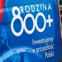 Niebieski baner z napisem "RODZINA 800+" i hasłem "Inwestujemy w przyszłość Polski". Widoczne uśmiechnięte dzieci.