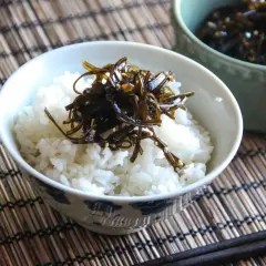 A bowl of white rice topped with dark, glistening tsukudani, a savory seaweed dish. This image hints at a delicious tsukudani recipe.