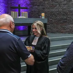 Frauen in der kirche: Eine Geistliche teilt Brot mit Gemeindemitgliedern.