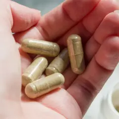 Kilka kapsułek leków na obniżenie kortyzolu w dłoni.