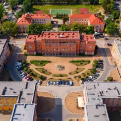 Osiedle Otylia w Tychach z lotu ptaka. Centralny budynek z pomarańczową fasadą, plac z fontanną i otaczające go bloki mieszkalne.