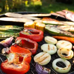 Kolorowe warzywa na grilla: papryka, cukinia, cebula, szparagi i kukurydza pieką się na ruszcie, tworząc apetyczny obraz.