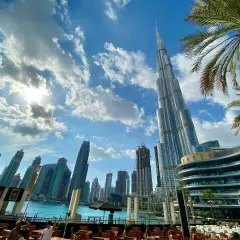 Widok na drapacze chmur w Dubaju, gdzie jest Burj Khalifa, z palmami i błękitnym niebem.