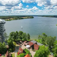 Wieża widokowa nad jeziorem, idealne miejsce na Kaszubach, co warto zobaczyć. Żaglówka na wodzie, lasy i chmury.