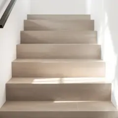 Escaliers en carrelage clair, sans joints apparents, avec un éclairage doux. On peut marcher sur du carrelage sans joint pour un look épuré.