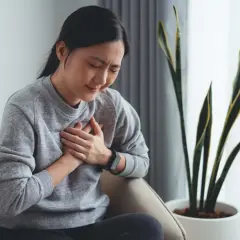 Mujer con dolor en el pecho, buscando cómo quitar acidez estomago.