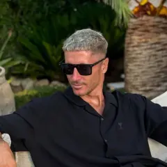 Robert Lewandowski w czarnej koszuli i okularach przeciwsłonecznych, relaksujący się w ogrodzie. Jego majątek robi wrażenie.