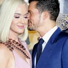 Katy Perry i Orlando Bloom w czułym uścisku. Ona w różowej sukni i masywnym naszyjniku, on w granatowym garniturze.