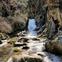Un río serpentea entre rocas y vegetación hasta una cascada en la ruta de las cascadas del Purgatorio.