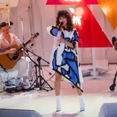 Wokalistka w sukience z geometrycznym wzorem śpiewa na scenie podczas MTV Unplugged Polska. Obok gra gitarzysta.