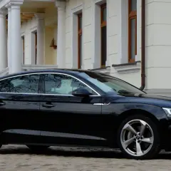Eleganckie, czarne Audi A5 z 2018 roku zaparkowane przed klasycznym budynkiem z kolumnami.