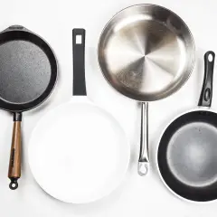 Vier Pfannen: Gusseisen, weiß beschichtet, Edelstahl und eine weitere beschichtete Pfanne. Jede aluminium oder edelstahl pfanne hat ihren Zweck.