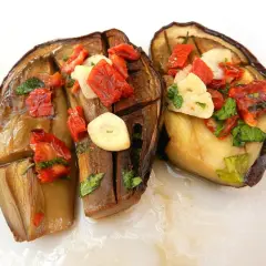 Melanzane alla sassarese, un piatto saporito con melanzane cotte, pomodori secchi, aglio e prezzemolo.
