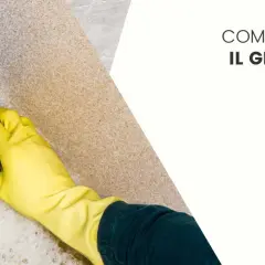 Mano con guanto giallo pulisce una superficie in granito con una spugna e schiuma.