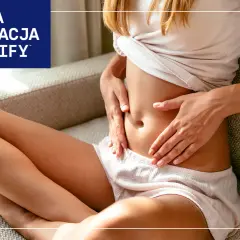 Kobieta trzyma się za brzuch, szukając ulgi co na gazy. Wiedza i edukacja by Labify.