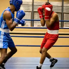Two boxers in a ring, one in blue, the other in red, showcasing the disciplined footwork and defensive stance characteristic of the cuban boxing style.