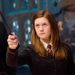 Bonnie Wright jako Ginny Weasley w filmach o Harrym Potterze, z różdżką w dłoni, gotowa do rzucenia zaklęcia.