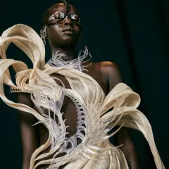 Mannequin portant une création avant-gardiste, un vêtement d'impression 3D aux formes organiques et futuristes, orné de détails argentés sur le visage.