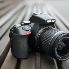 Czarny aparat Nikon D3300 z obiektywem na drewnianym tle.