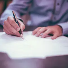 Ręka pisze na papierze, wypełniając dokumenty dotyczące podatku od spadku po wujku.