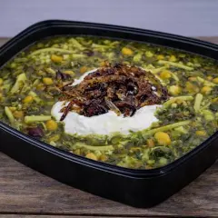 En skål med grön ash reshteh, en persisk örtsoppa med nudlar, kikärtor och linser, toppad med yoghurt och friterad lök.