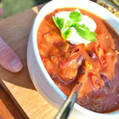 Aksamitna zupa meksykańska z pulpecikami, ozdobiona kleksem śmietany i świeżą kolendrą, z plasterkami chili.