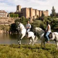 Paseo a caballo junto al río en Buitrago de Lozoya, con el castillo medieval al fondo.