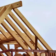 Holzkonstruktion für den dachstuhl aufbau. Balken bilden ein stabiles Gerüst gegen den hellblauen Himmel.