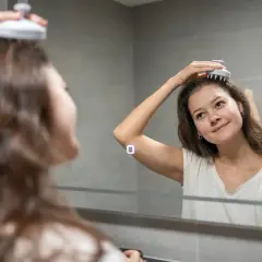 En kvinna njuter av en avkopplande scalp massage framför en spegel.