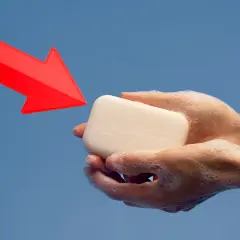 Manos enjabonadas sostienen jabón neutro. Una flecha roja apunta hacia él, indicando su uso.