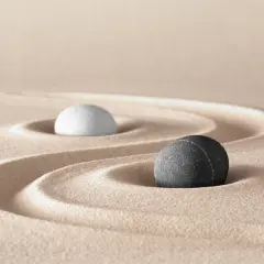 Due pietre, una bianca e una grigia, su sabbia rastrellata, evocano le yin e yang caratteristiche di equilibrio e dualità.