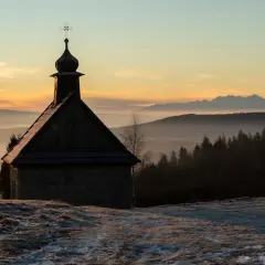 Kapliczka na Koskowej Górze o wschodzie słońca, z mgłami i ośnieżonymi szczytami w tle.