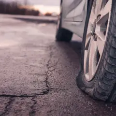Rueda de coche desinflada en carretera mojada. ¡Qué mala suerte, pinchar ruedas coche!