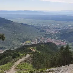 Panoramica mozzafiato con un sentiero tortuoso tra i pini, che conduce a un villaggio incastonato tra le colline. Buti cosa vedere in questo paesaggio incantevole.