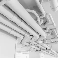 Skomplikowany system białych rur pehd biegnie pod sufitem, tworząc labirynt instalacji.