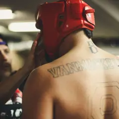 En fighter med röd hjälm och tatueringar på ryggen förbereds inför match. Kanske undrar du vad betyder MMA?