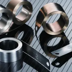 Rollos de cinta de acero inoxidable o aluminio, con reflejos sobre una superficie rayada.