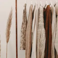 Ubrania w odcieniach beżu i brązu wiszą na wieszakach. Inspiracja do tworzenia stylizacji, jak łączyć kolory.
