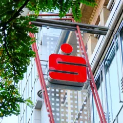 Rotes Sparkassen-Logo an einem Gebäude. Die Frage "wie lange bucht die Sparkasse" wird hier nicht beantwortet, aber das Logo ist gut sichtbar.