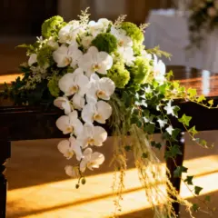Elegancki bukiet ślubny z białych orchidei i zielonych dodatków, który może wpłynąć na bukiet ślubny cena.