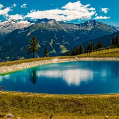 Vandra i Bad Gastein, en klarblå fjällsjö speglar majestätiska berg under en molnig himmel.
