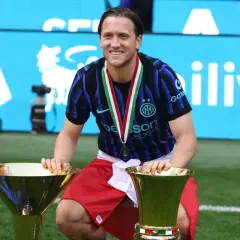 Piłkarz z dwoma pucharami na tle napisu Serie A. Tabela ligi włoskiej w tle.