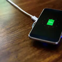 Telefon na ładowarce indukcyjnej osiągnął 100%. Warto ładować telefon do pełna, by zapewnić mu długą żywotność baterii.