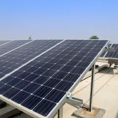 Rząd paneli fotowoltaicznych na dachu, gotowych do montażu. Czyste niebo i słońce zapowiadają zieloną energię.